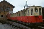 Ein Zug der Schweizer Schynige Platte Bahn vor dem Wagenschuppen in Wilderswil mit einer Ellok der Baureihe He 2/2 (1983)