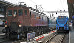 Der blaue TPF RABe 527 198 als RE Fribourg-Bulle im Bahnhof Fribourg auf die baldige Abfahrt wartend neben dem Extrazug mit der 100-jährigen Be 4/7 12504.