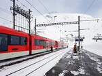 Matterhorn-Gotthard-Bahn__Zug der Matterhorn-Gothardbahn in der Station Oberalppass. Die  Schneehüenerstock-Kabinenbahn im Hintergrund führt auf ca. 2.600m.__25-02-2024