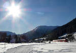 Auf dem Winterwanderweg von Davos Dorf nach Davos Frauenkirch blendet nicht nur die Sonne, es kommt auch der Regio von Filisur nach Davos Platz entgegen. Davos, 25.12.2024