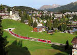 Regionalzug von Arosa nach Chur hat soeben den Tunnel beim Bahnhof Arosa verlassen und fährt talwärts Richtung Chur. An 2. Stelle verkehrt der Bärenwagen: eine Attraktion für die Kinder mit Bücher, Bilder und Wettbewerb. Das Bild wurde vom Balkon einer Ferienwohnung aufgenommen. Arosa, 10.10.2023