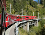 Der Regionalzug von Arosa nach Chur überquert eine Brücke zwischen St. Peter-Molinis und Lüen-Castiel. Lüen, 13.10.2023