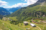 Der Bernina Express hat Alp Grüm gerade verlassen und befährt die berühmte Kurve talwärts Richtung Tirano. Gut zu erkennen, dass zusätzlich ein offener Panoramawagen angehängt wurde. Aufnahme vom 30. Juni 2018, 12:16