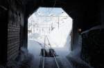14.01.2010 - Einfahrt in den Bahnhof Ospizio Bernina. Links neben dem Tunnel ist die Schneefrsse in einem Schopf  versteckt . Bild wurde aus dem Fahrgastraum aufgenommen. Im Allegra hat der Fahrgast eine Scheibe, durch welche man wunderbar auf die Strecke sehen kann.