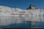 Ein Allegra fährt am 29. Dezember 2016 mit dem Regio 1644 Tirano - St. Moritz dem mit Schwarzeis bedeckten Lago Bianco entlang. Dahinter erhebt sich der 2599 Meter hohe Piz Campasc.