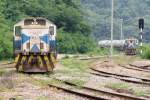 Während die TPIPL 33-005 (ex CK5 006) eine Pause hält, nähert sich im Hintergrund auf der Anschlußbahn die TPIPL 33-003 (ex CK5 004) mit einem Zementwagenzug der Hin Lap Station;