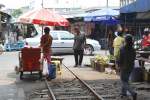 Bf. Mae Klong am 27.Mrz 2010, Blick von der Bahnhofshalle ber die Strasse auf Strecken-KM 33,675. Der Marktzustand ist wieder hergestellt und nichts deutet darauf hin, da hier ein Zug gefahren ist.