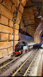 80 016 tourt mit einem Flachwagen an den Tischen des Erlebnis-Restaurants  Lakomativ  in Budapest (HU) vorbei.