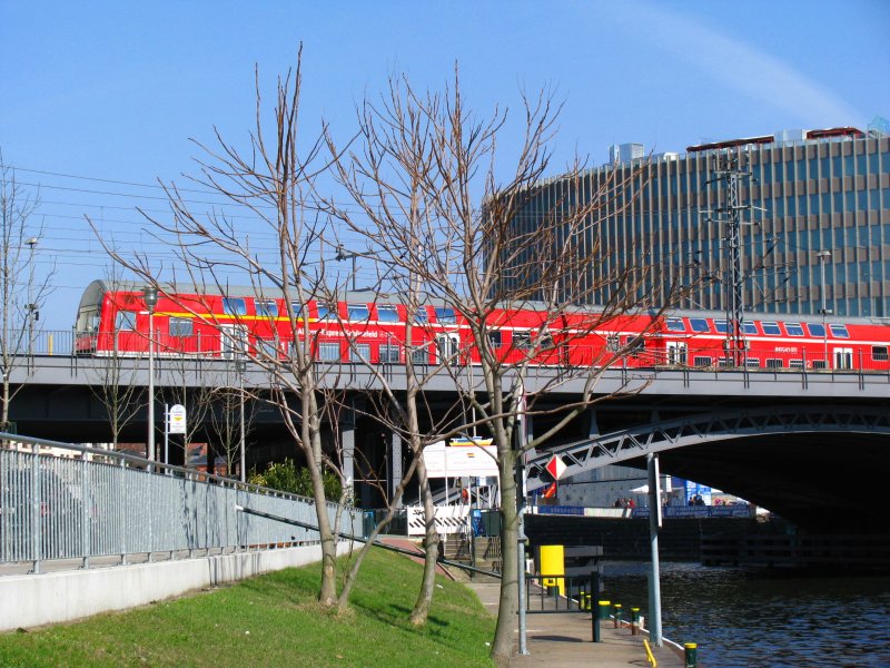 Vom Spreeufer beim Bahnhof Berlin Friedrichstrasse aus habe ich dieses Bild gemacht. Ein RE fhrt hier am 31.Mrz 2009 in Richtung Flughafen Schnefeld.
Was denkt ihr von der Bildgestaltung mit den laublosen Bumen im Vordergrund?