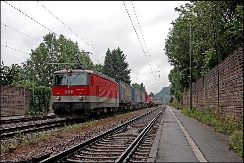 Whrend im Hotel hinter der Lrmschutzwand noch viele Gste schlafen, unterbricht die 1144 210 mit einem Kombizug die Morgendliche Ruhe. (08.07.2008)
